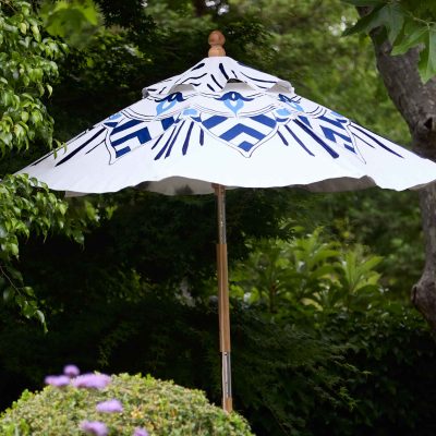 colorful custom patio umbrella painted by Teale Hatheway of pearl and maude - beautiful poolside space with blue and white