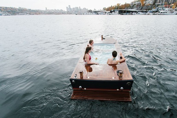 Stay warm while adventuring into fall: A wooden hot tub boat floats on a lake.