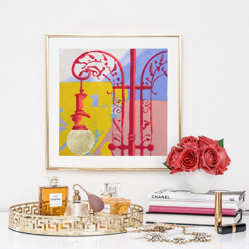 Delicate But Durable is a yellow, red, pink and periwinkle hand embellished print by Teale Hatheway. Here, this fine art print is seen framed and surrounded by luxurious perfume bottles, books and roses.