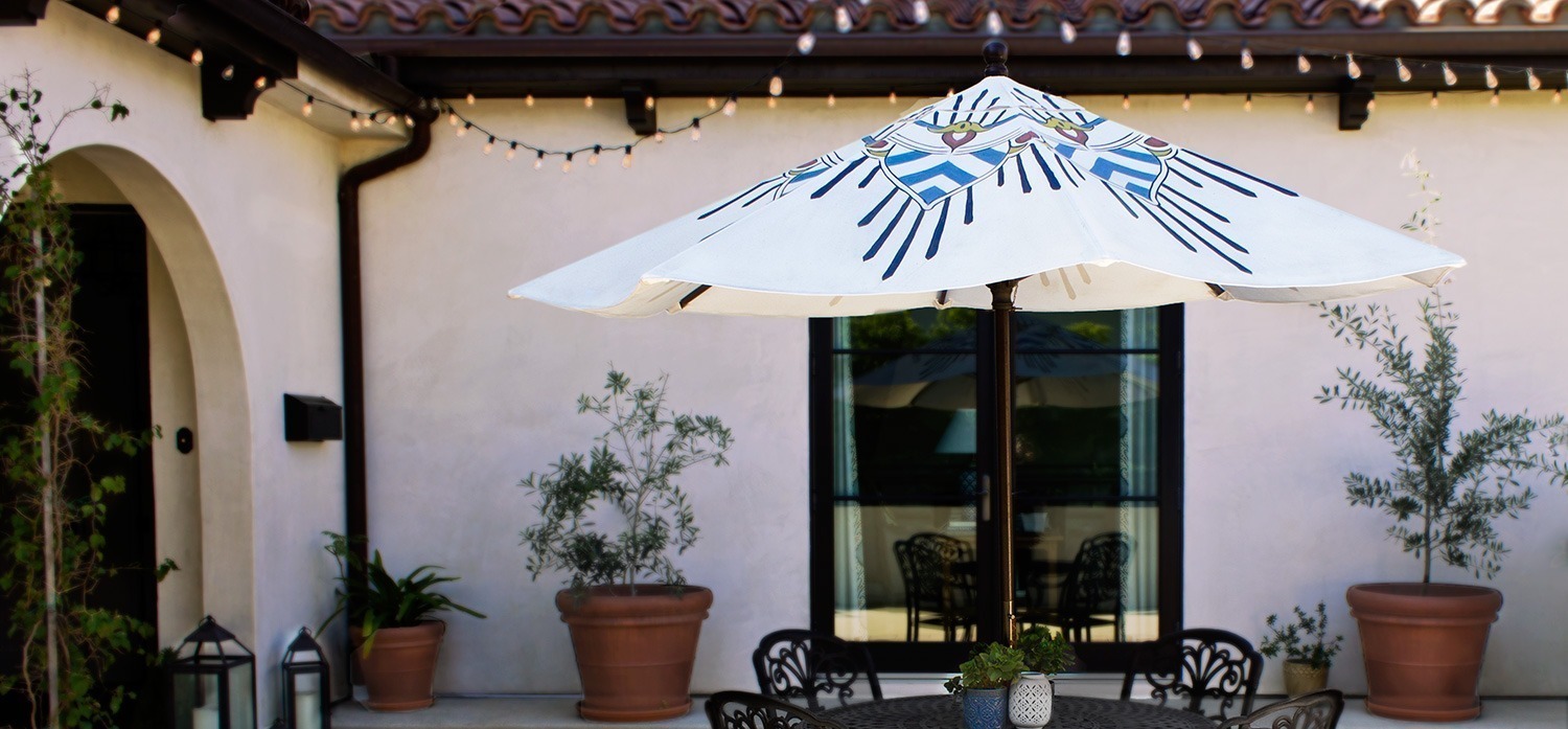 beautiful blue and white custom patio umbrella in a Spanish style courtyard by pearl and maude