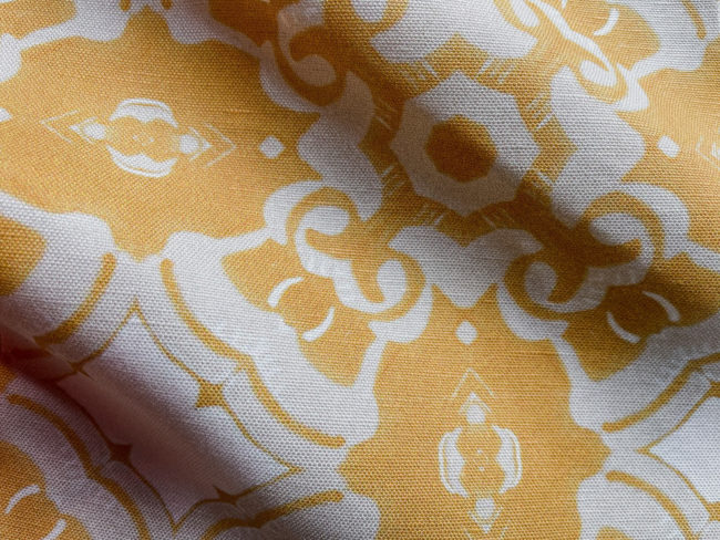 A fabric swatch of Pearl & Maude's medallion pattern Alexandria in daisy yellow, cream and white