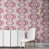Pearl & Maude's abstract botanical Carmen nonwoven vellum wallpaper in berry pink and grey installed in a beautiful living room with white and brass furniture.