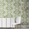 Pearl & Maude's abstract botanical Carmen nonwoven vellum wallpaper in moss green, white and grey installed in a beautiful living room with white and brass furniture.
