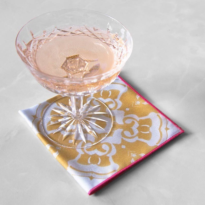 Alexandria Cloth Cocktail Napkin in daisy yellow with a crystal champagne glass