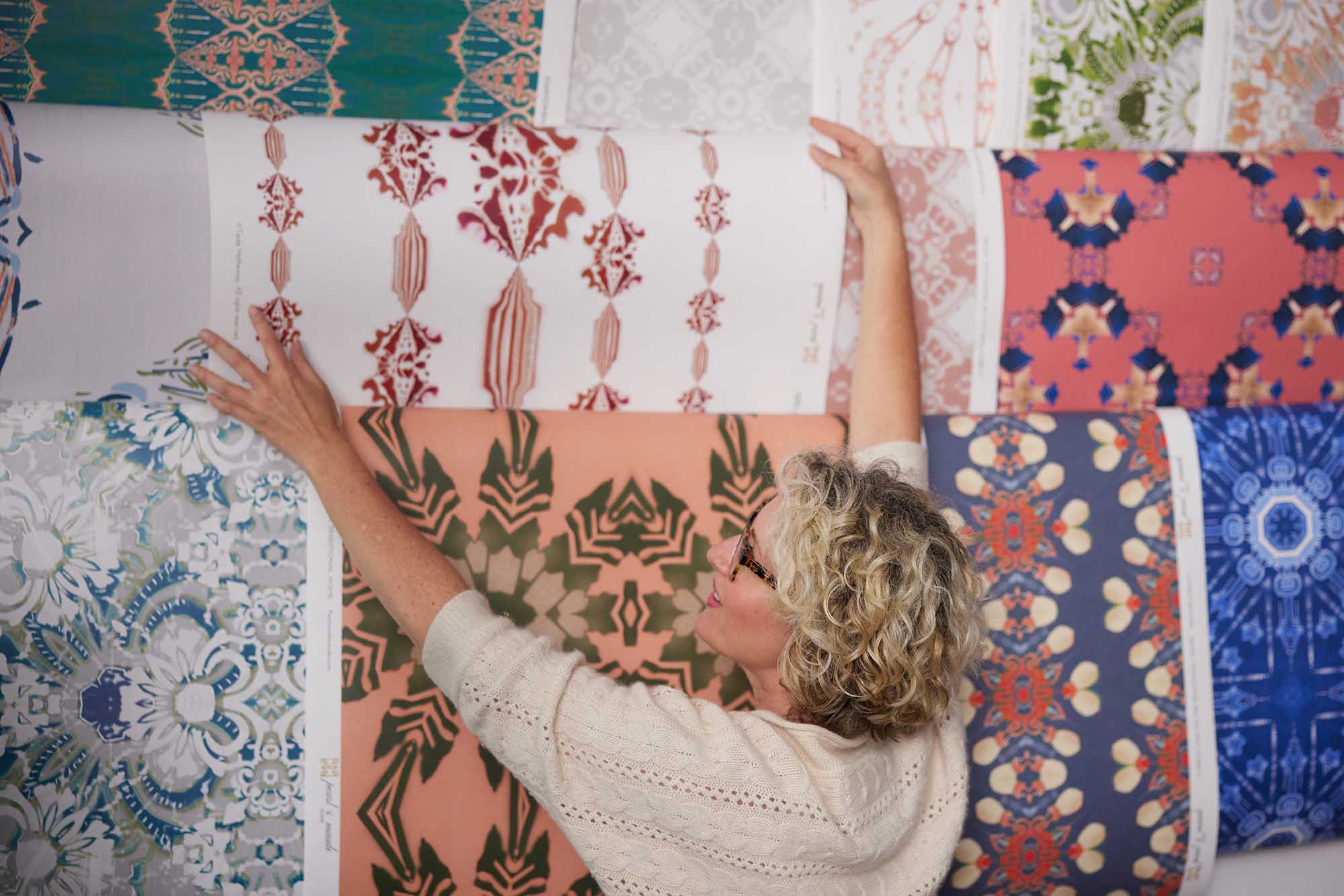 Teale Hatheway, founder and designer at Pearl & Maude Home, in the studio arranging her wallpaper designs