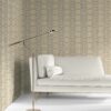 our Ruguru geometric tile wallpaper, with an intricate repeat, in the Silt Brown and beige colorway. Installed on the wall of a room decorated with fine white velvet seating and high end furniture