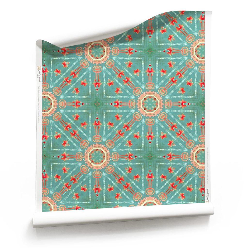 A roll of "Beaufort,” turquoise starburst wallpaper is a multicolor pattern. In the turquoise, pink and coral colorway, it draws inspiration from the laid-back, bohemian beach bungalows of 1960s Southern California.