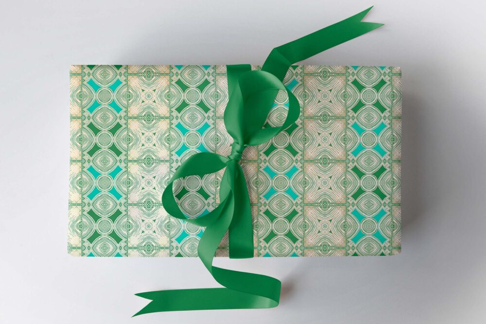 Green aqua and gold gift wrapping paper on a gift box with a purple ribbon