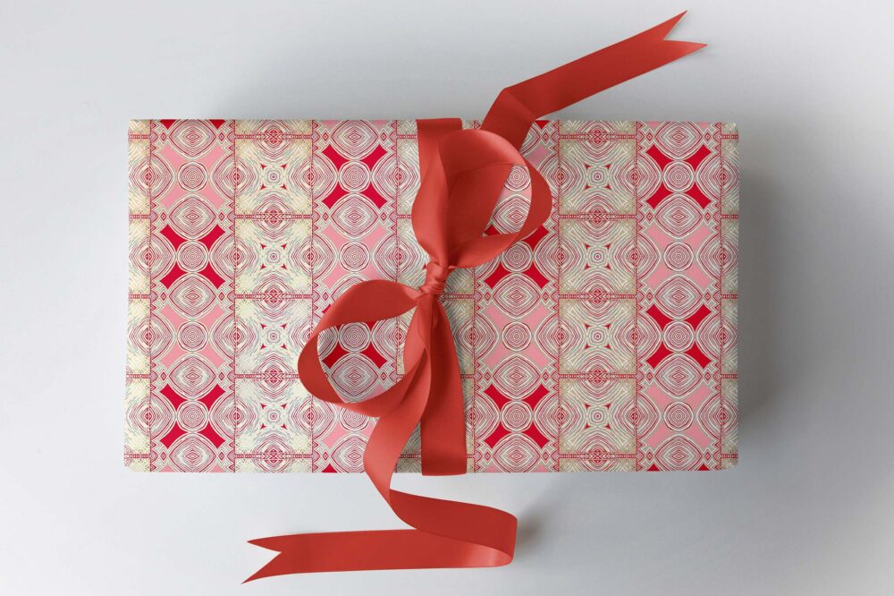 red pink and gold gift wrapping paper on a gift box with a purple ribbon